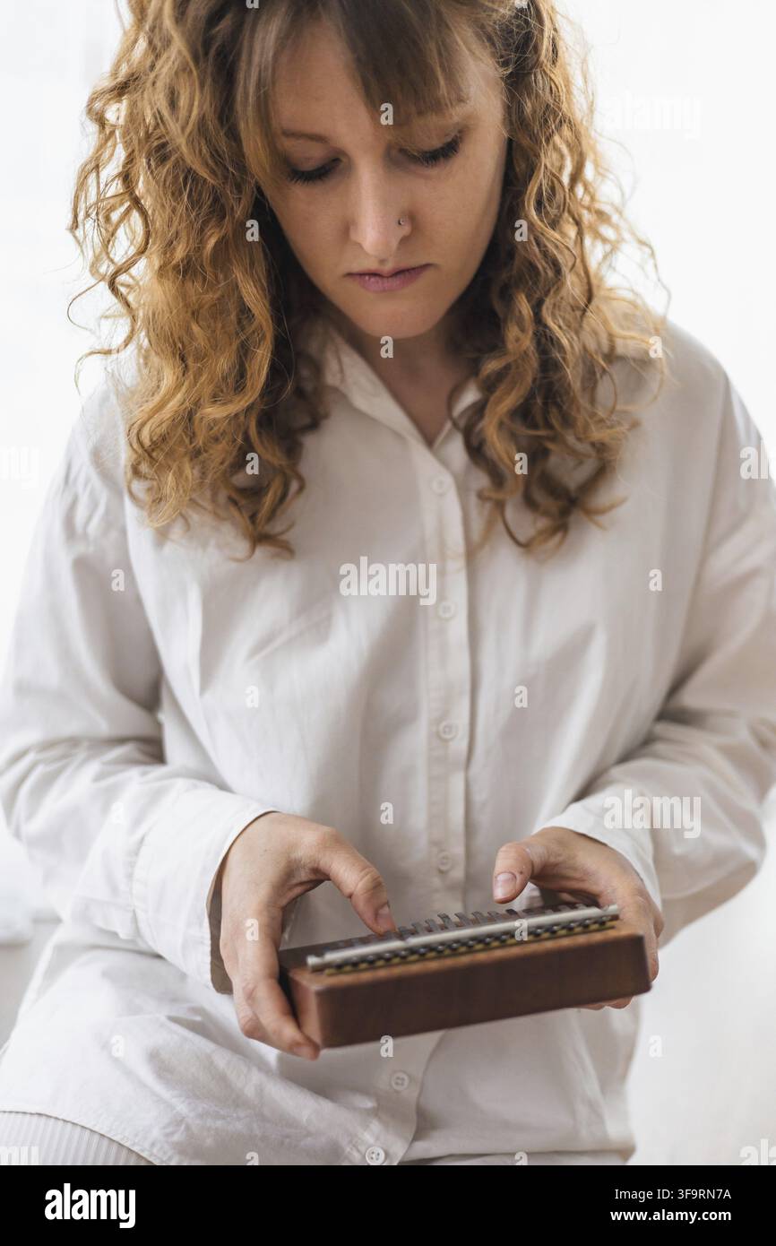 Une femme concentrée explore le kalimba, révélant un engagement musical réfléchi Banque D'Images
