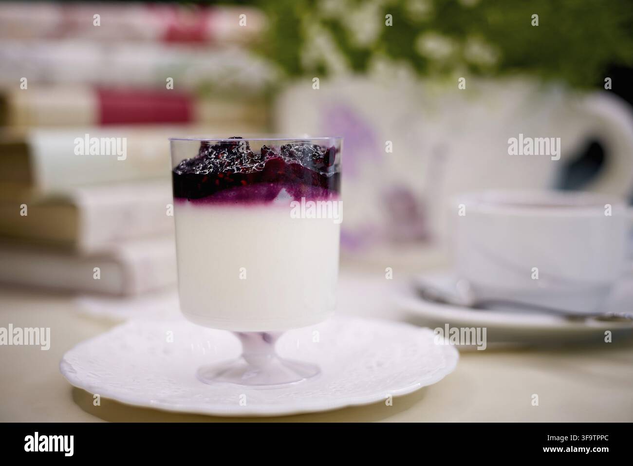 Dessert aux myrtilles avec du thé sur la table avec des fleurs et des livres Banque D'Images