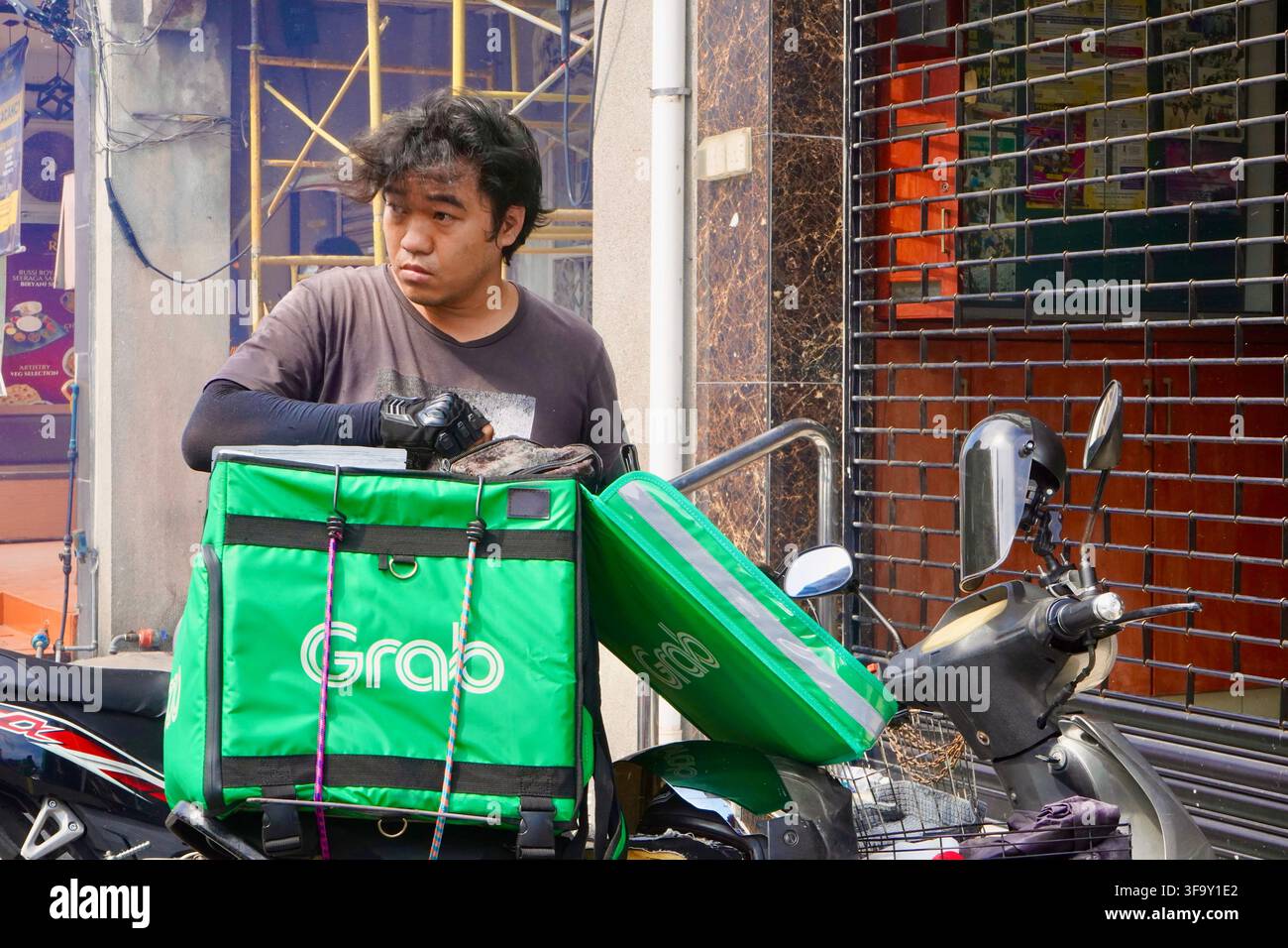Livreur de repas déballant la commande d'un scooter à George Town, Penang Malaisie Banque D'Images
