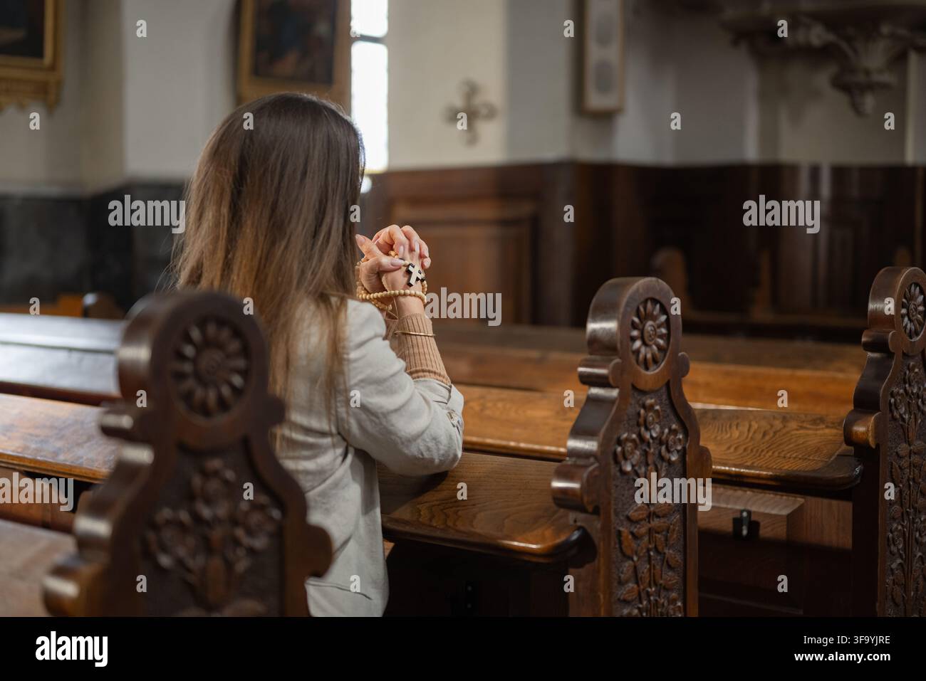 Une femme prie dans une église catholique européenne pendant la messe solennelle, montrant dévotion et foi dans un moment de culte silencieux. Banque D'Images