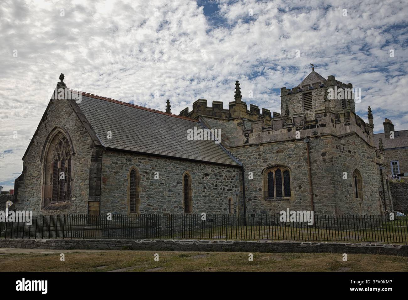 Vue extérieure de l'église St Cybi à Holyhead, Anglesey, dans le nord du Pays de Galles, Royaume-Uni, montrant des murs en pierre, un toit en ardoise, une grande fenêtre gothique et une clôture périmétrique. Banque D'Images
