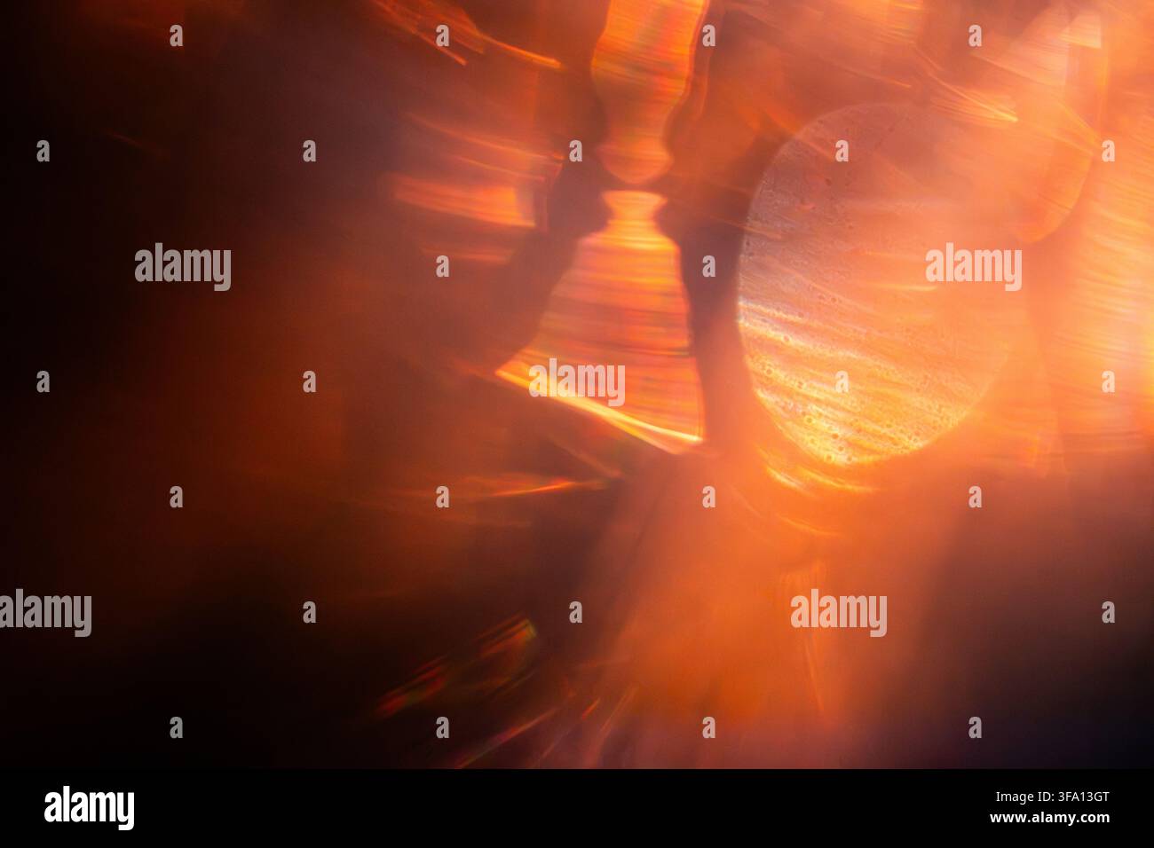 Composition abstraite de traînées de lumière orange vives et de bokeh circulaire lumineux, créant un fond chaleureux et énergique avec des réflexions floues, des flares et un Banque D'Images
