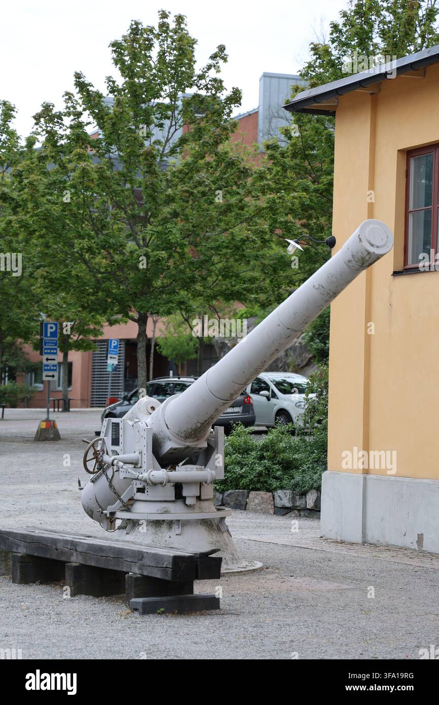 Un canon naval blanc exposé devant la Torpedverkstaden sur Skeppsholmen, à Stockholm, en Suède, photographié par une journée d'été ensoleillée. Banque D'Images