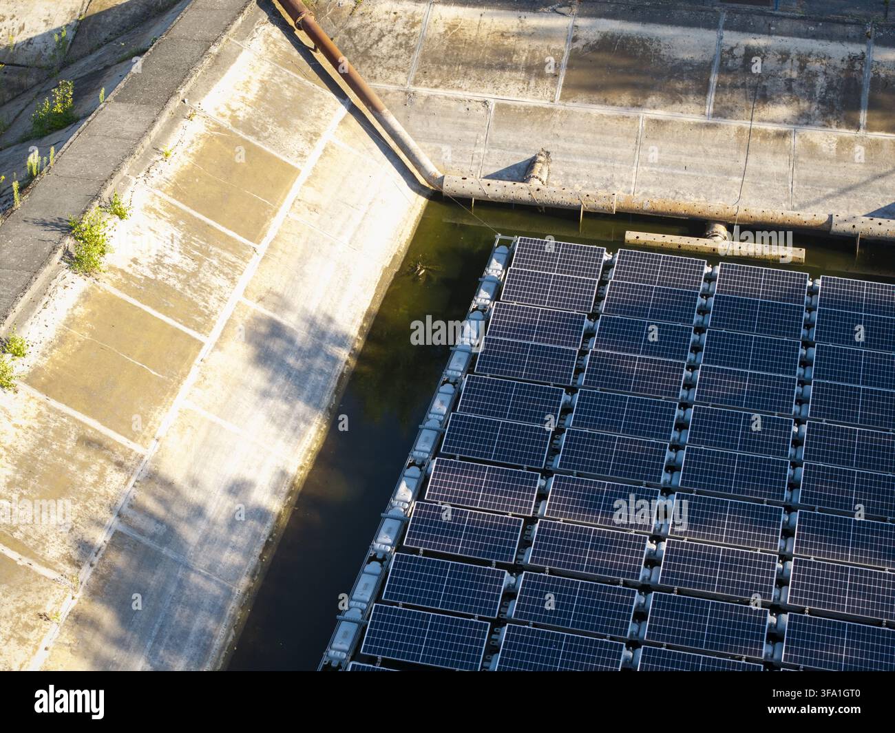 Vue aérienne de panneaux solaires flottants installés sur un réservoir d'eau avec des talus en béton en Pologne. Banque D'Images