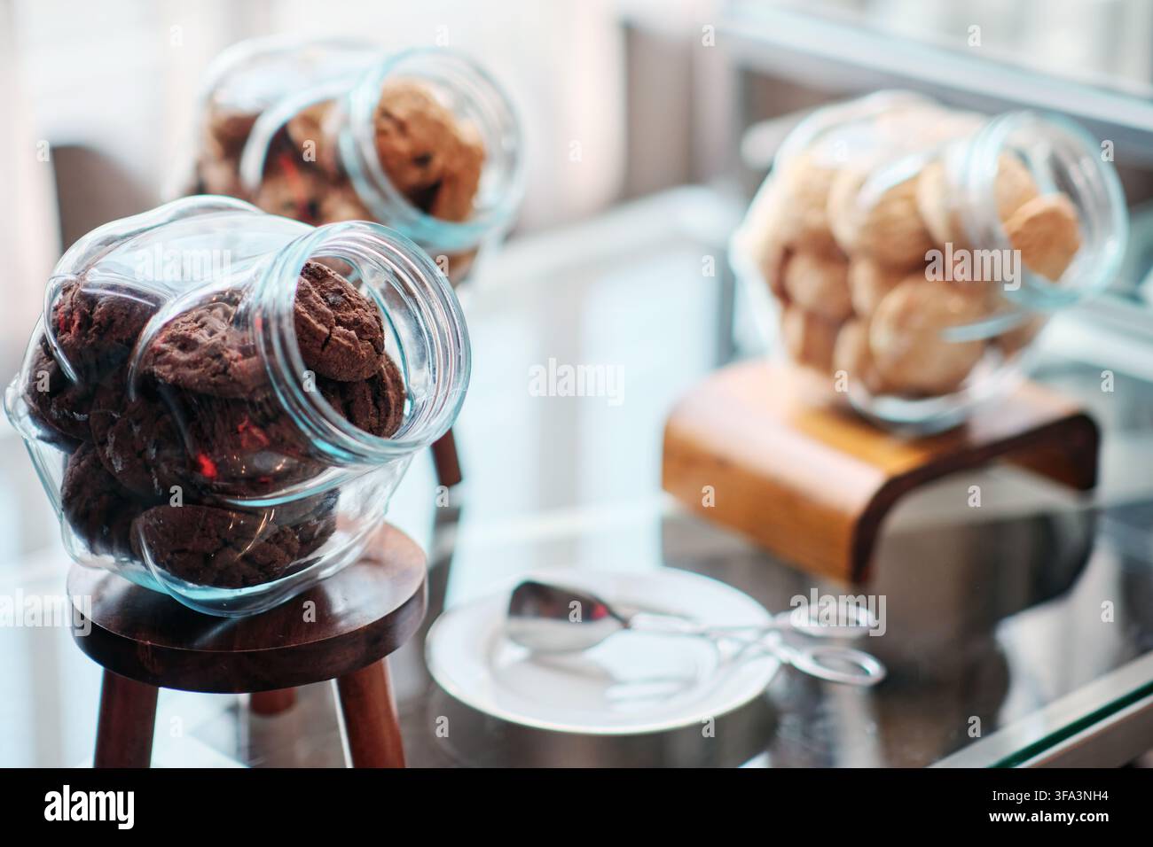 Des biscuits au chocolat noir dans un bocal et deux autres bocaux remplis de biscuits au lait sont posés sur la table lors d'une réunion professionnelle, pause thé et café Banque D'Images