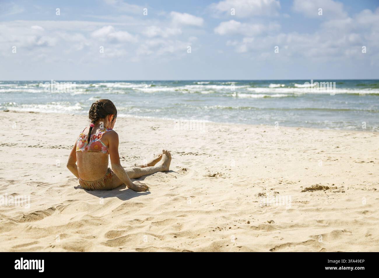 Une petite fille assis en vacances d'été sur la plage du Courlande en Lituanie – pour des concepts autour des voyages en famille et du style de vie en Banque D'Images