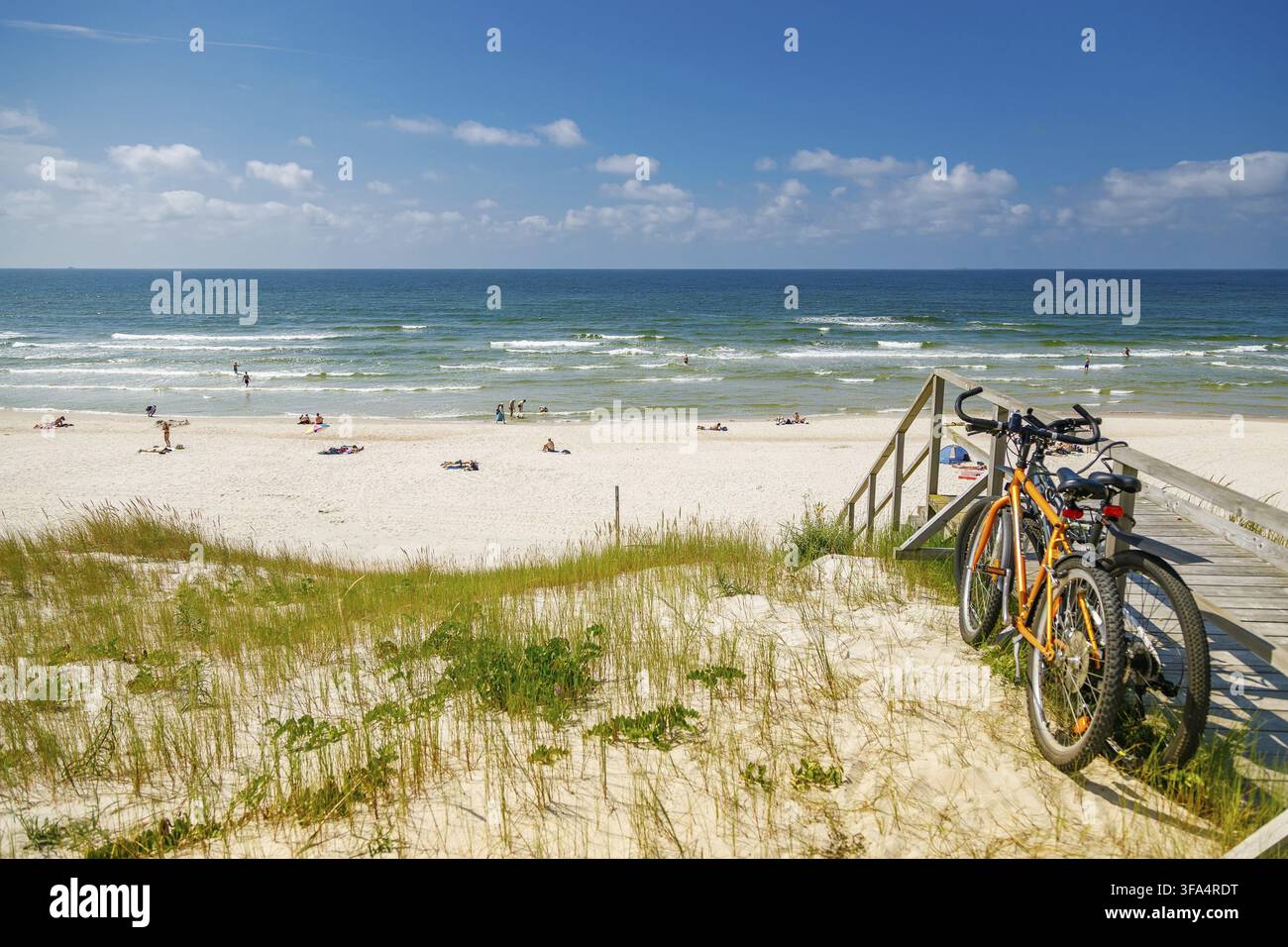 Vélos garés près d'un escalier en bois surplombant une plage de sable bondée et la mer Baltique à la Courlande Kurière pour le tourisme estival ou les loisirs côtiers Banque D'Images