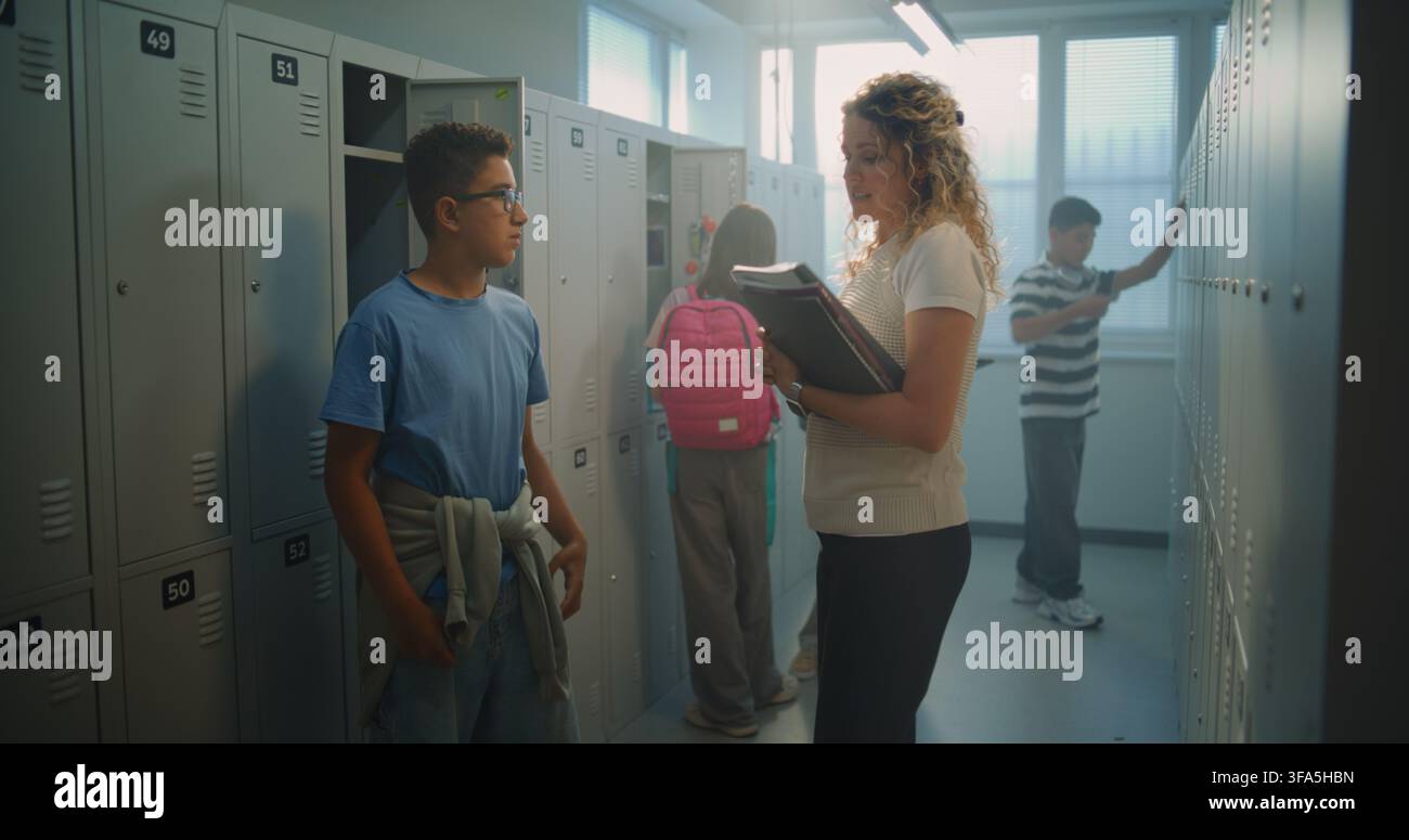 Enseignante encourageante félicite un élève pour ses progrès académiques tout en discutant dans le vestiaire. Réussite scolaire, motivation, renforcement positif et communication saine enseignant-élève. Banque D'Images