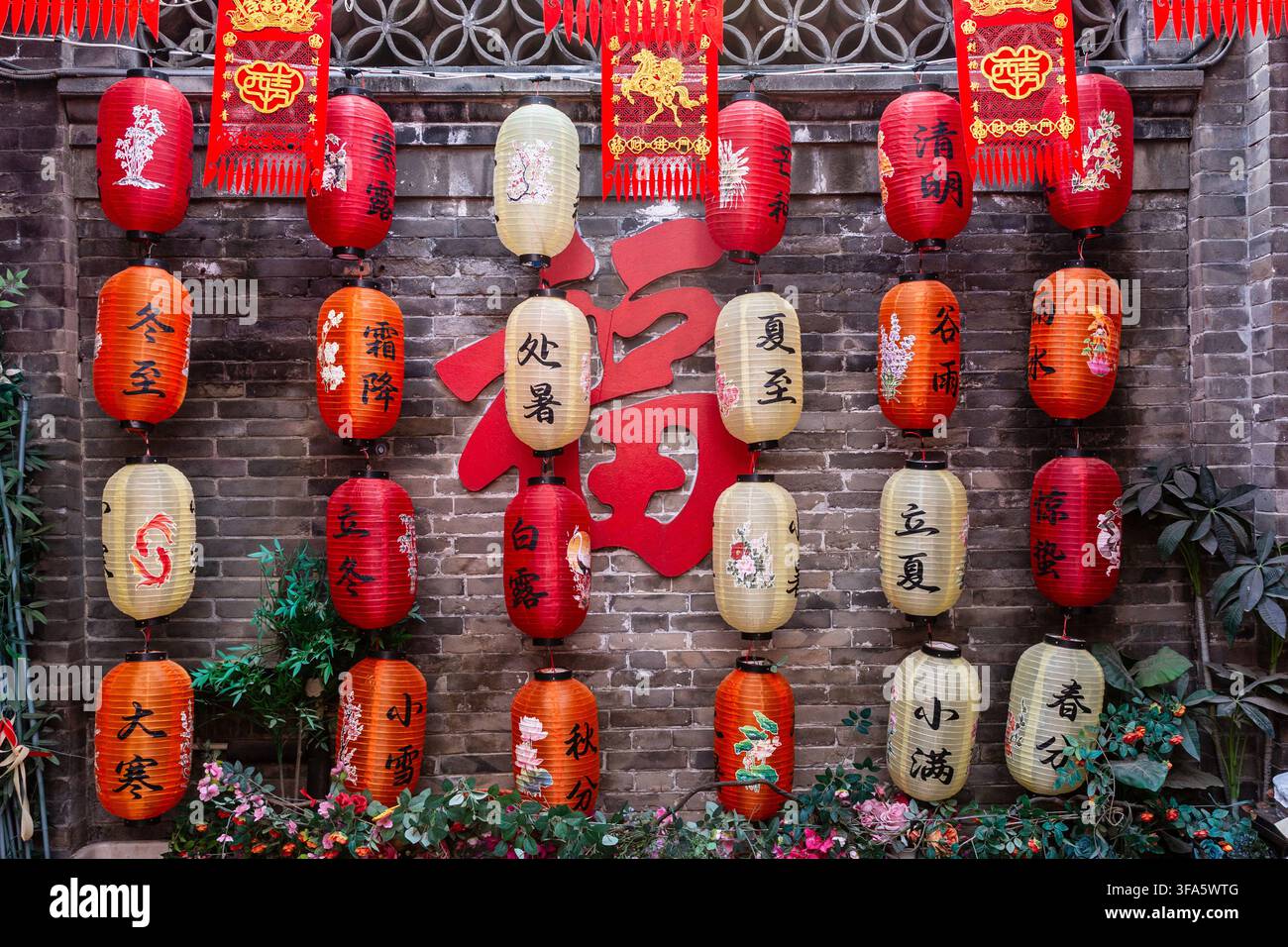 Lanternes chinoises traditionnelles représentant les 24 termes solaires sur un vieux mur de briques avec le caractère Fu Banque D'Images