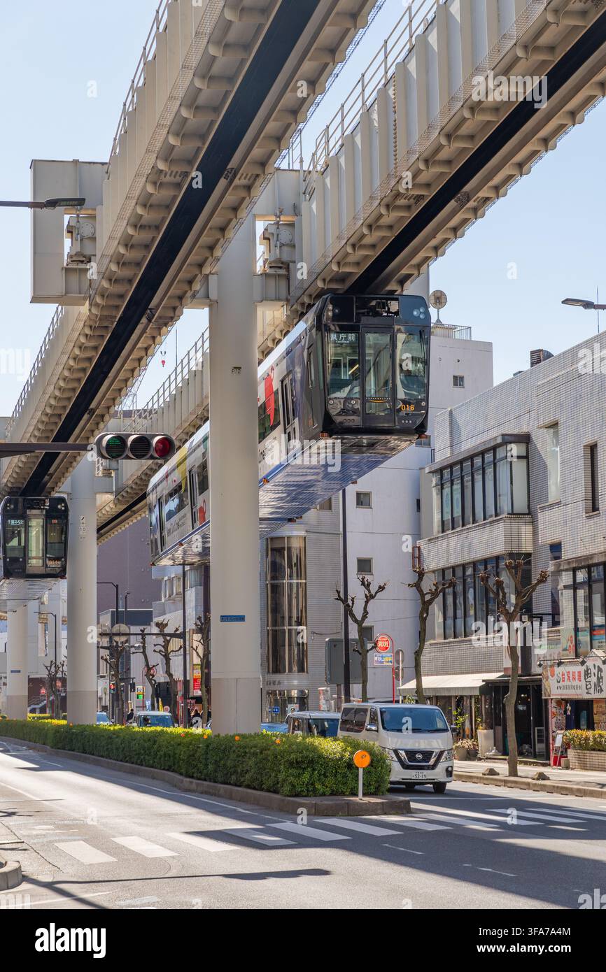 Chiba, Japon-1er février 2026 : Train monorail suspendu moderne circulant au-dessus d'une rue urbaine animée par une journée ensoleillée avec circulation automobile et routière Banque D'Images