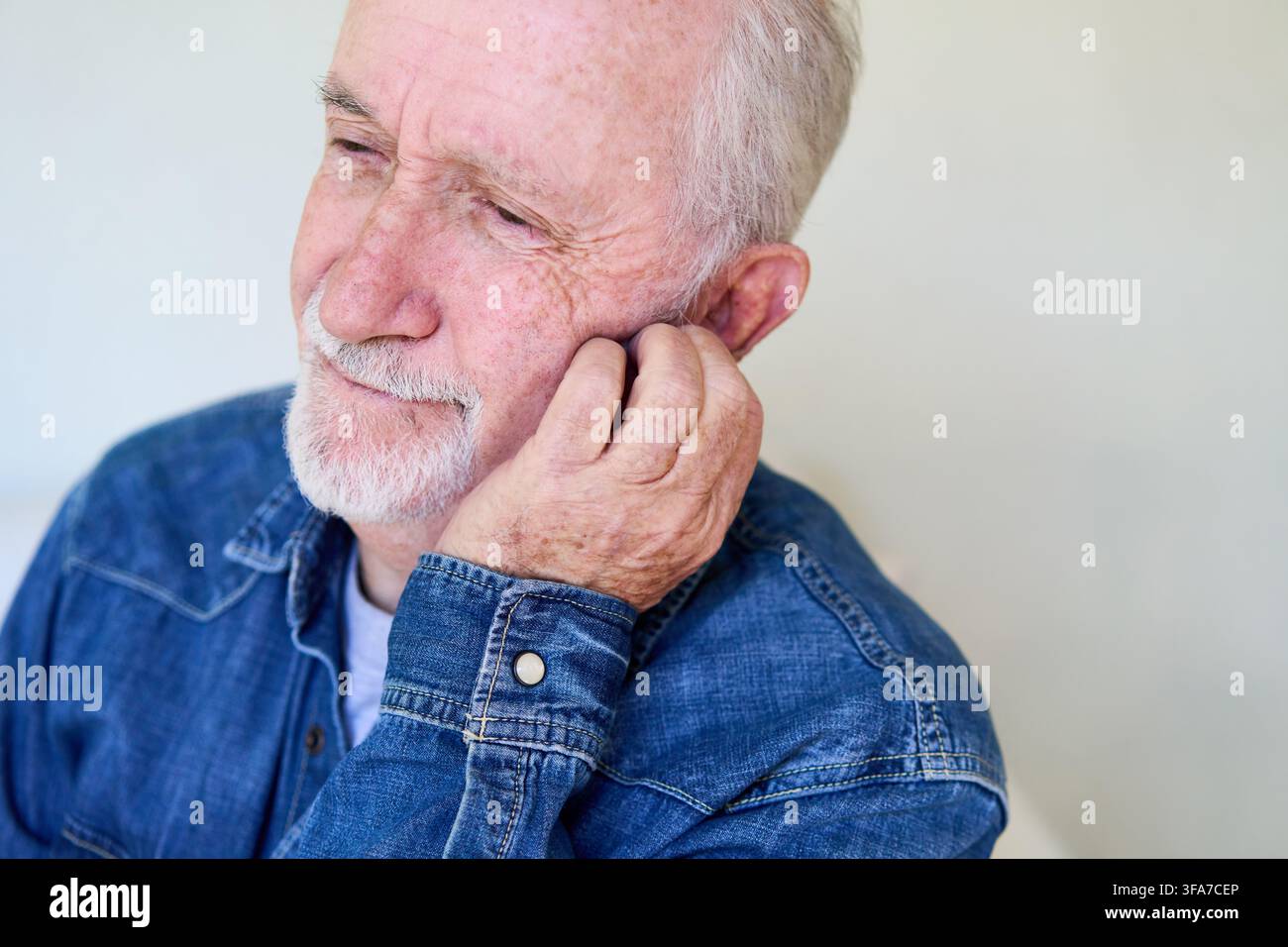 Homme âgé ressentant des douleurs d'oreille ou des problèmes auditifs, concept de soins de santé et de bien-être pour les personnes âgées. Vieillesse et inconfort, un portrait rapproché d'un homme âgé Banque D'Images
