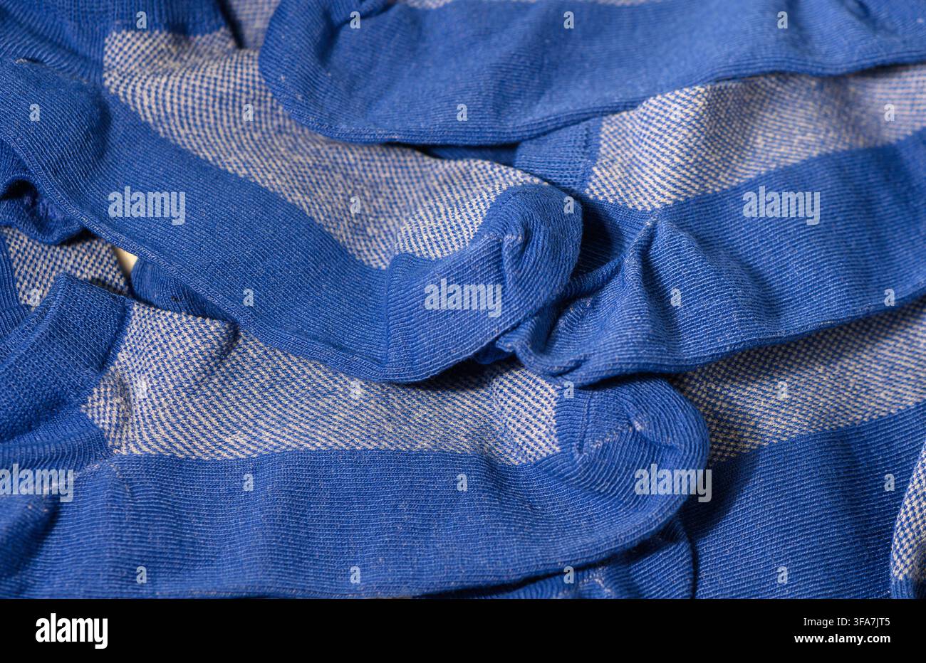 Une photographie macro détaillée affichant un tas désordonné et superposé de chaussettes à motifs bleues et blanches, mettant l'accent sur les riches tons bleus, la texture tricotée, Banque D'Images