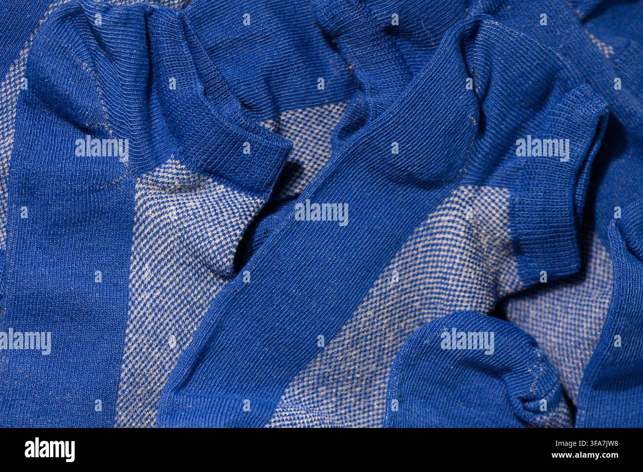 Une photographie macro montrant une vue rapprochée et détaillée de la texture tricotée et des côtes des plusieurs chaussettes bleues arborant une pa blanche contrastante Banque D'Images
