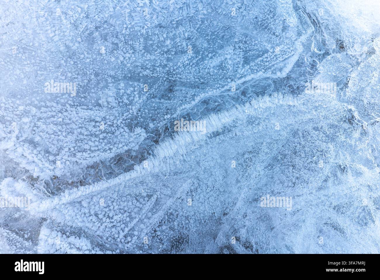 Texture cristalline de glace naturelle formant un motif abstrait gelé sur une surface hivernale. Banque D'Images