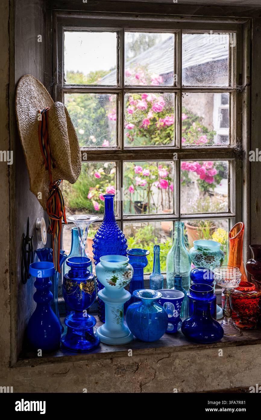 Chapeau de paille et verrerie bleue sur le rebord de la fenêtre dans la serre d'une maison géorgienne dans les frontières écossaises, Royaume-Uni. Banque D'Images