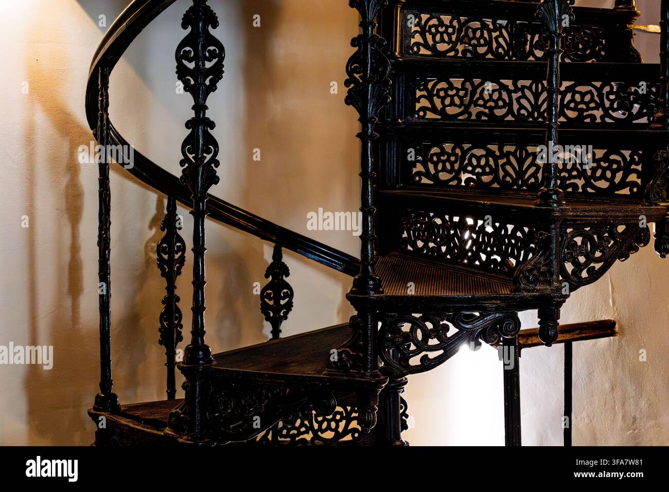 Escalier en colimaçon noir en fonte avec des détails ornés de rampes en bois décoratifs dans un design d'intérieur vintage. Banque D'Images