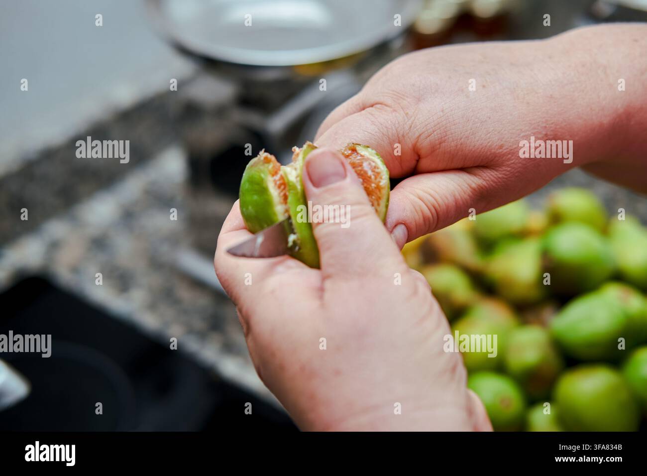 Mains pélant une figue fraîche, préparant des fruits pour la cuisine ou la consommation Banque D'Images