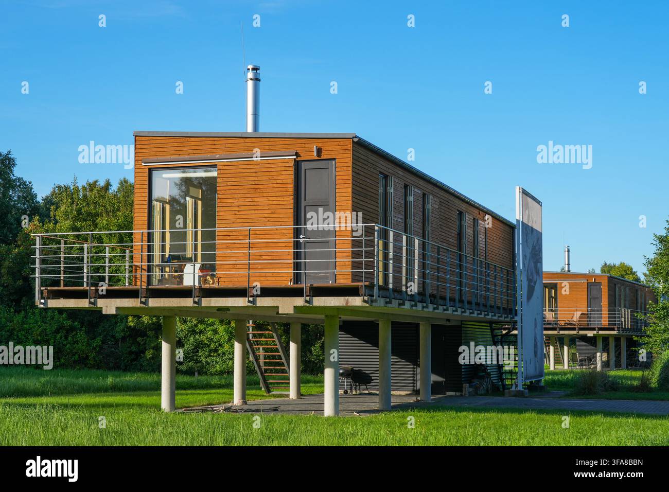 Pavilosta, Lettonie - 09 août 2026 : Maisons résidentielles modernes revêtues de bois sur pilotis en béton avec balcons et grandes fenêtres dans un paysage verdoyant Banque D'Images