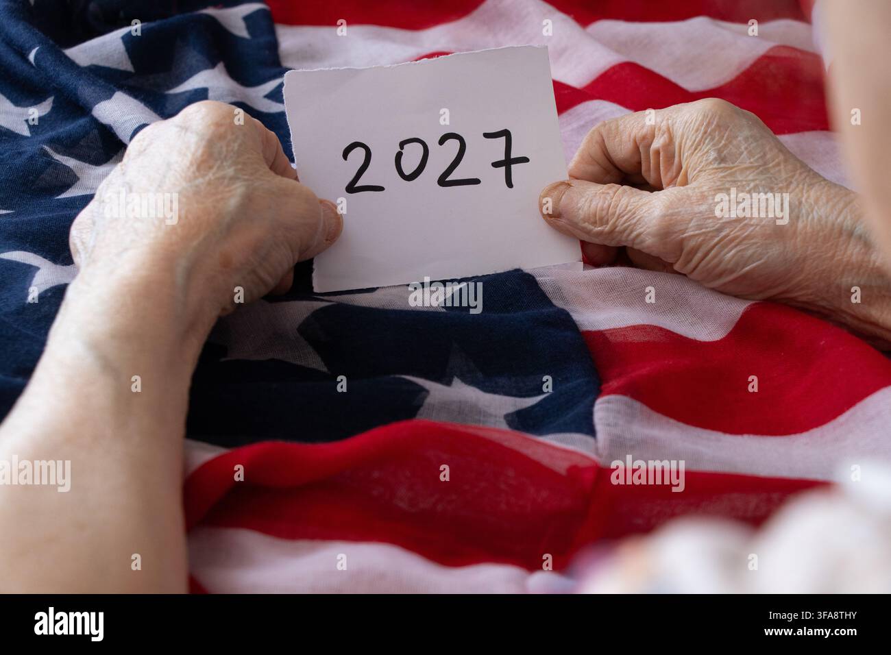 Une femme âgée tient une carte en papier portant le mot 2027 sur fond du drapeau américain, sur le thème du Nouvel An, du calendrier et de Holi Banque D'Images
