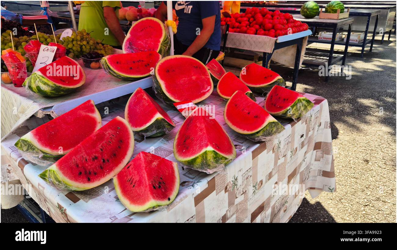 Des tranches de pastèque rouge fraîche enveloppées dans du plastique sont exposées sur un étal de marché de rue en Croatie. Banque D'Images