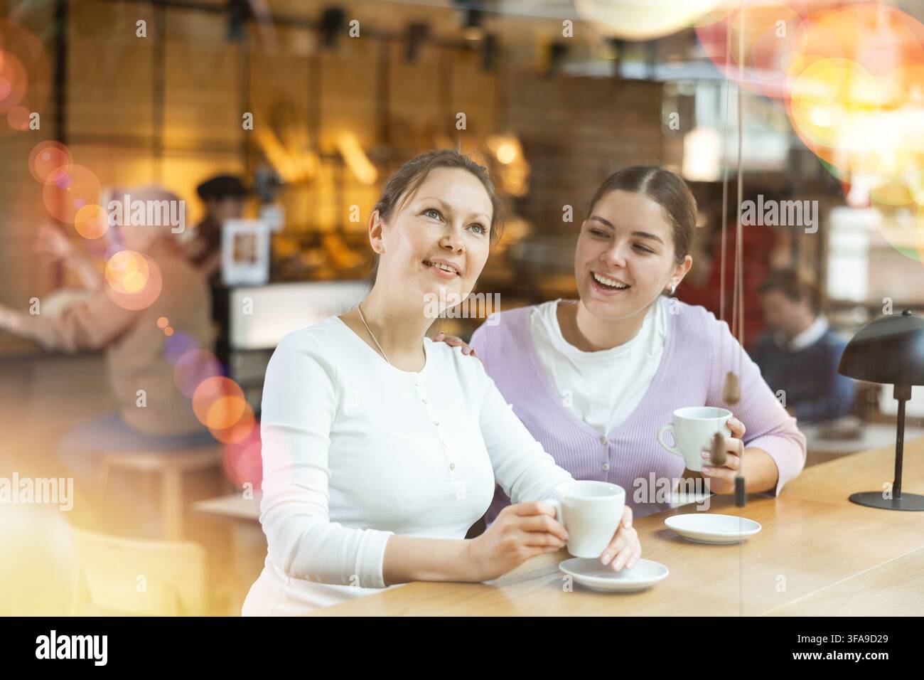 Deux amies joyeuses appréciant leur café dans un café confortable Banque D'Images