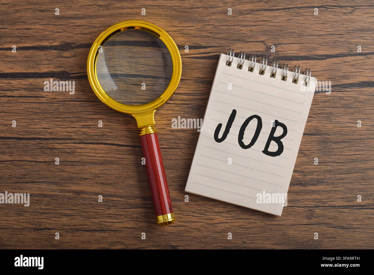 Texte d'offre d'emploi sur un bloc-notes avec une loupe sur un bureau en bois. Concept de recherche d'emploi, recrutement, embauche, planification de carrière Banque D'Images