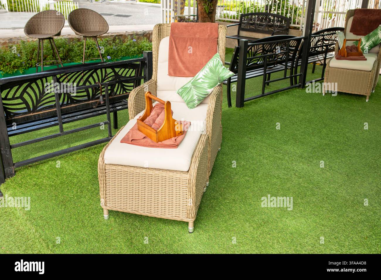 Chaise de massage en osier avec coussin et serviette sur de la pelouse artificielle verte en plein air, Thaïlande Banque D'Images