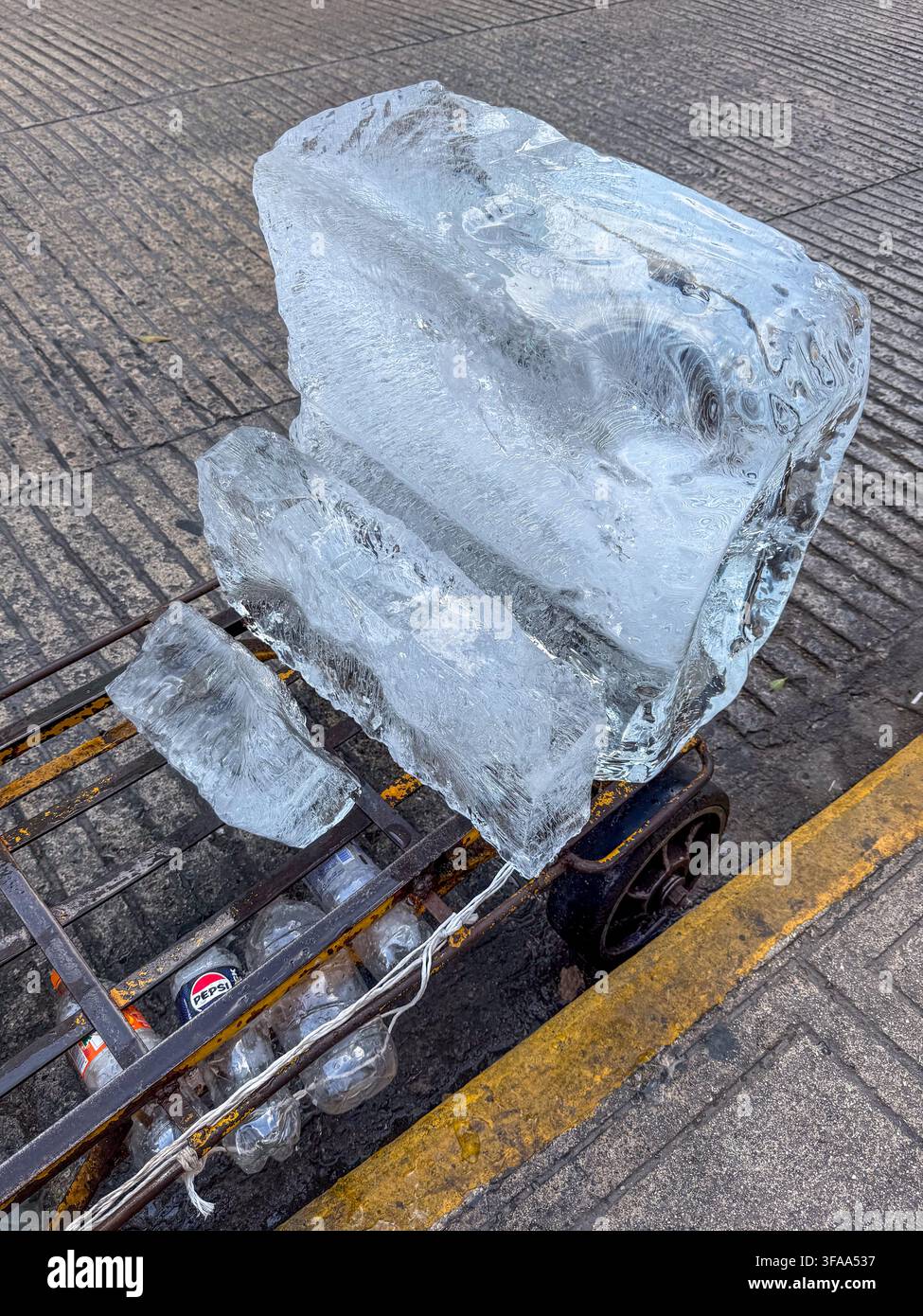 Un gros bloc de glace sur un chariot de rue à Mérida, Yucatán, Mexique, symbolisant les besoins de refroidissement et l'adaptation quotidienne à la chaleur extrême et au changement climatique Banque D'Images