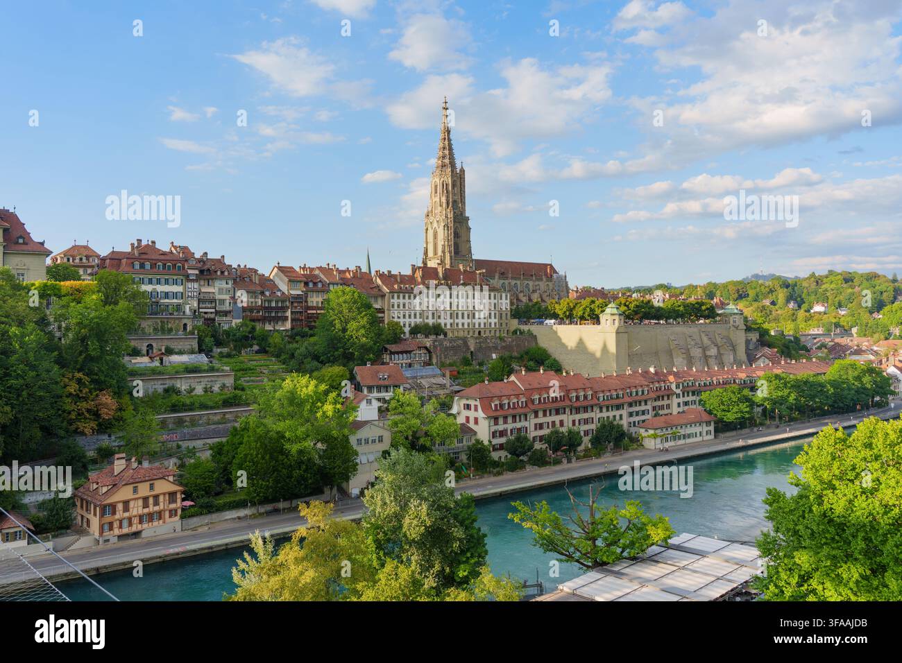 Paysage urbain historique de Berne mettant en scène la majestueuse cathédrale du Münster de Berne dominant les maisons traditionnelles et les eaux bleues vives de la rivière Aare Banque D'Images