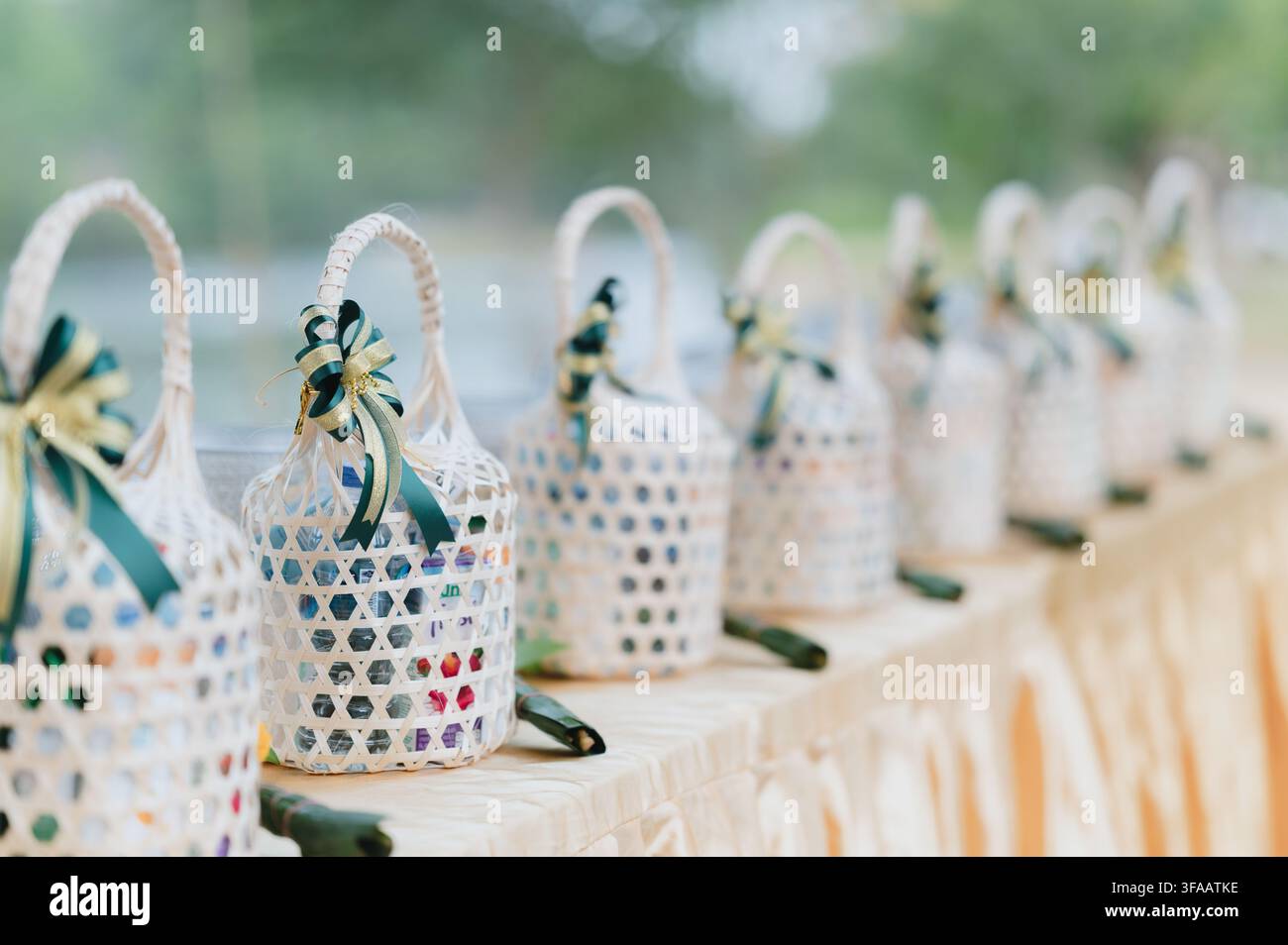 Paniers-cadeaux en bambou avec des rubans verts sur une nappe dorée lors d'une cérémonie bouddhiste en plein air. Banque D'Images