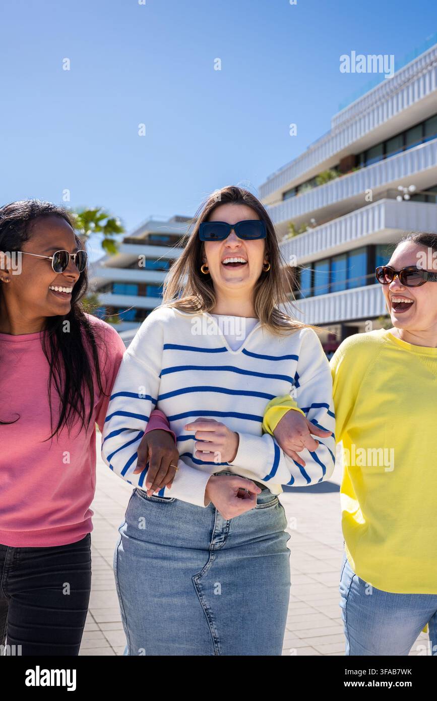 Trois amies marchant et riant en plein air par une journée ensoleillée Banque D'Images