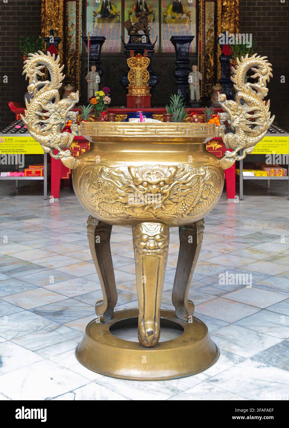 Brûleur d'encens en laiton doré orné de motifs de dragons à l'intérieur du temple ancestral Chan She Shu Yuen à Kuala Lumpur, Malaisie, reposant sur un sol en marbre Banque D'Images