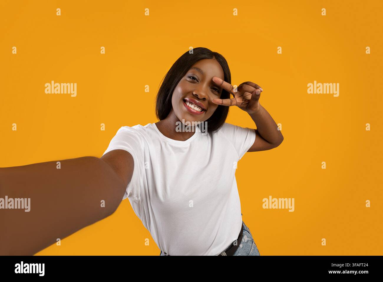 Joyeuse femme noire prenant le selfie sur fond jaune Banque D'Images