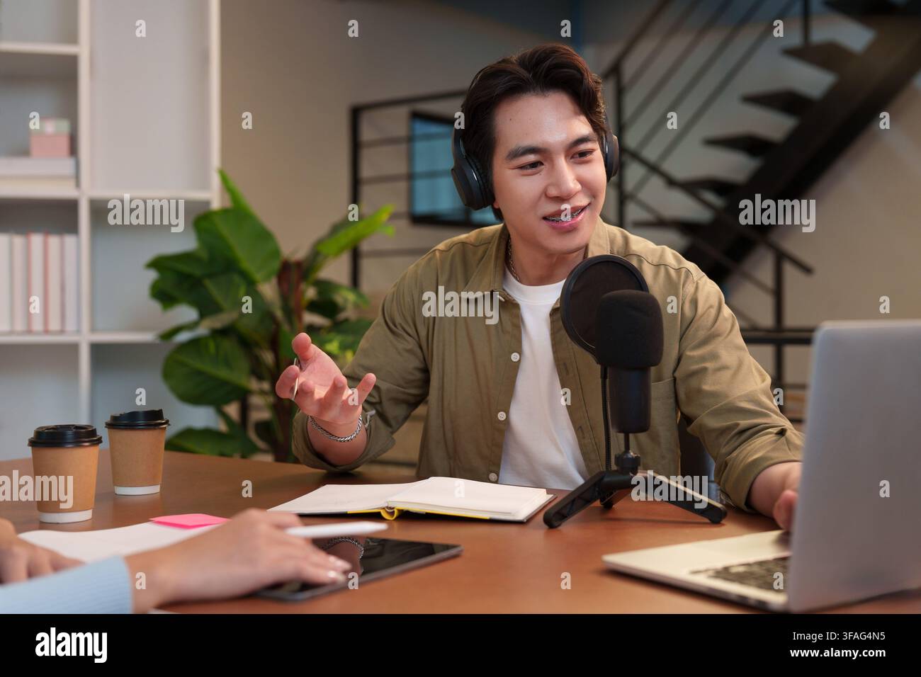 Hôte asiatique de podcast parlant dans un micro pendant l'enregistrement Banque D'Images