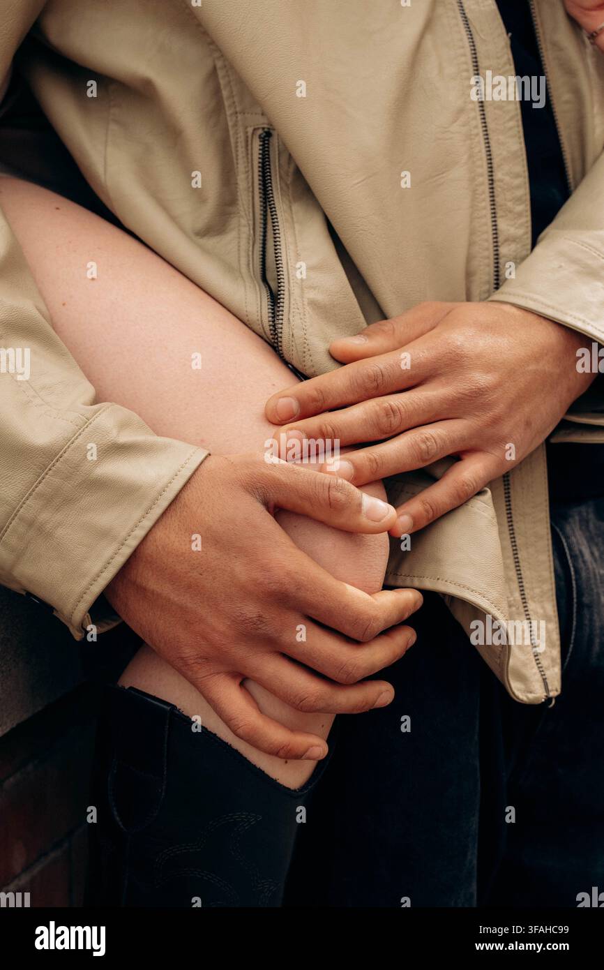 Close-up de mains reposant doucement sur le genou d'une personne, transmettant chaleur et confiance. L'image capture un moment de réconfort et de soutien, illustrant une ca Banque D'Images
