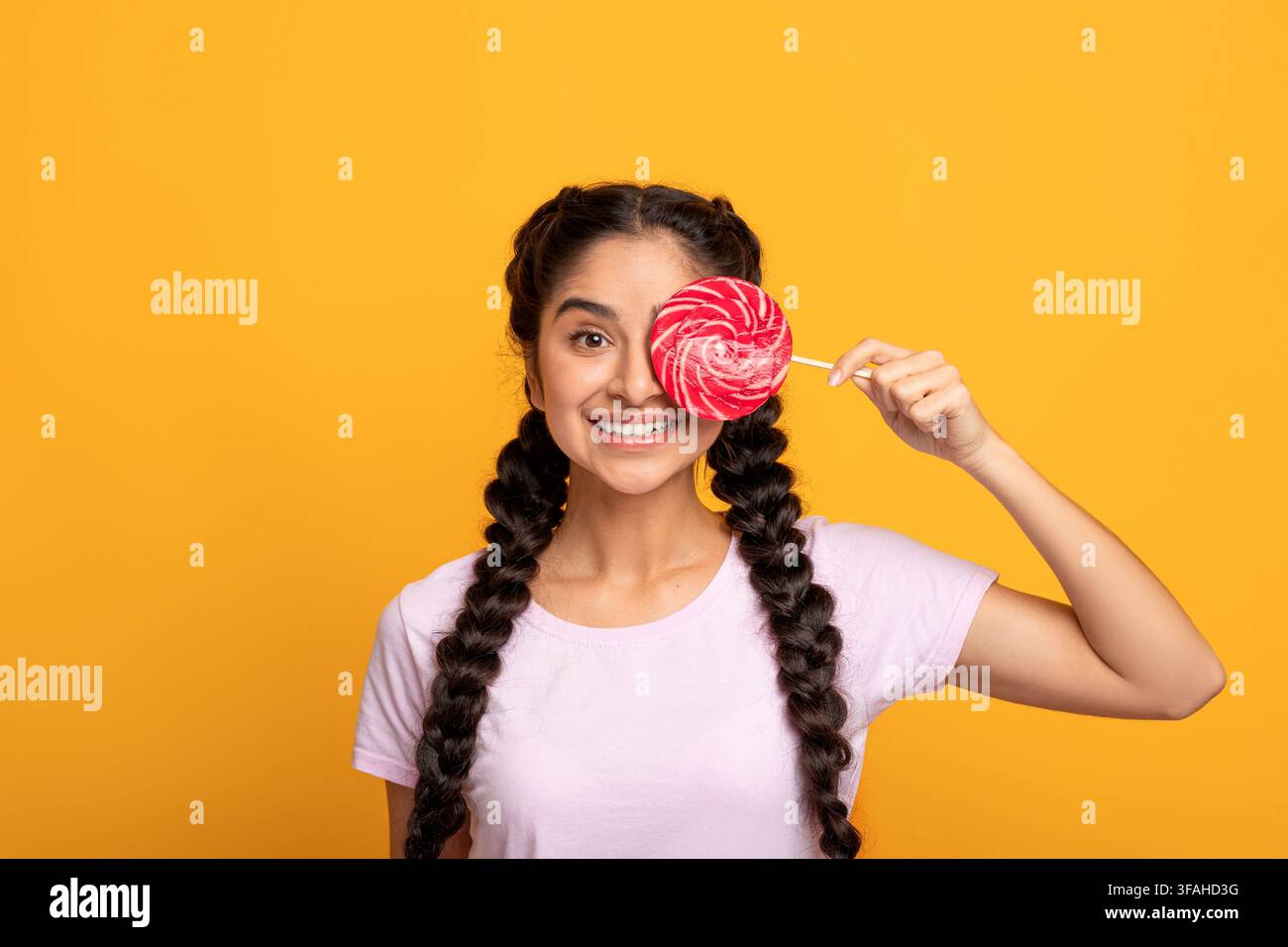 Femme indienne tenant une lollipop, couvrant un oeil avec des bonbons Banque D'Images