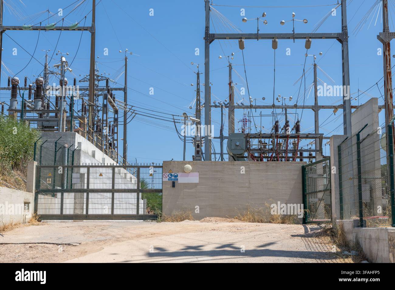 Une vue d'une sous-station électrique industrielle présentant une infrastructure complexe, des tours métalliques et de nombreux câbles sur un ciel éclatant Banque D'Images