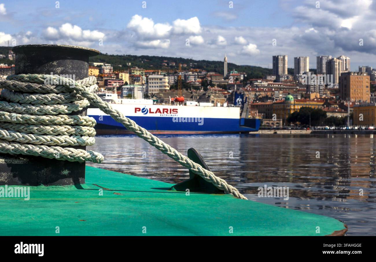 Câbles d'amarrage sur un taquet au premier plan avec le porte-automobiles Polaris et une vue de la ville dans le port de Rijeka, baie de Kvarner, Croatie. Banque D'Images
