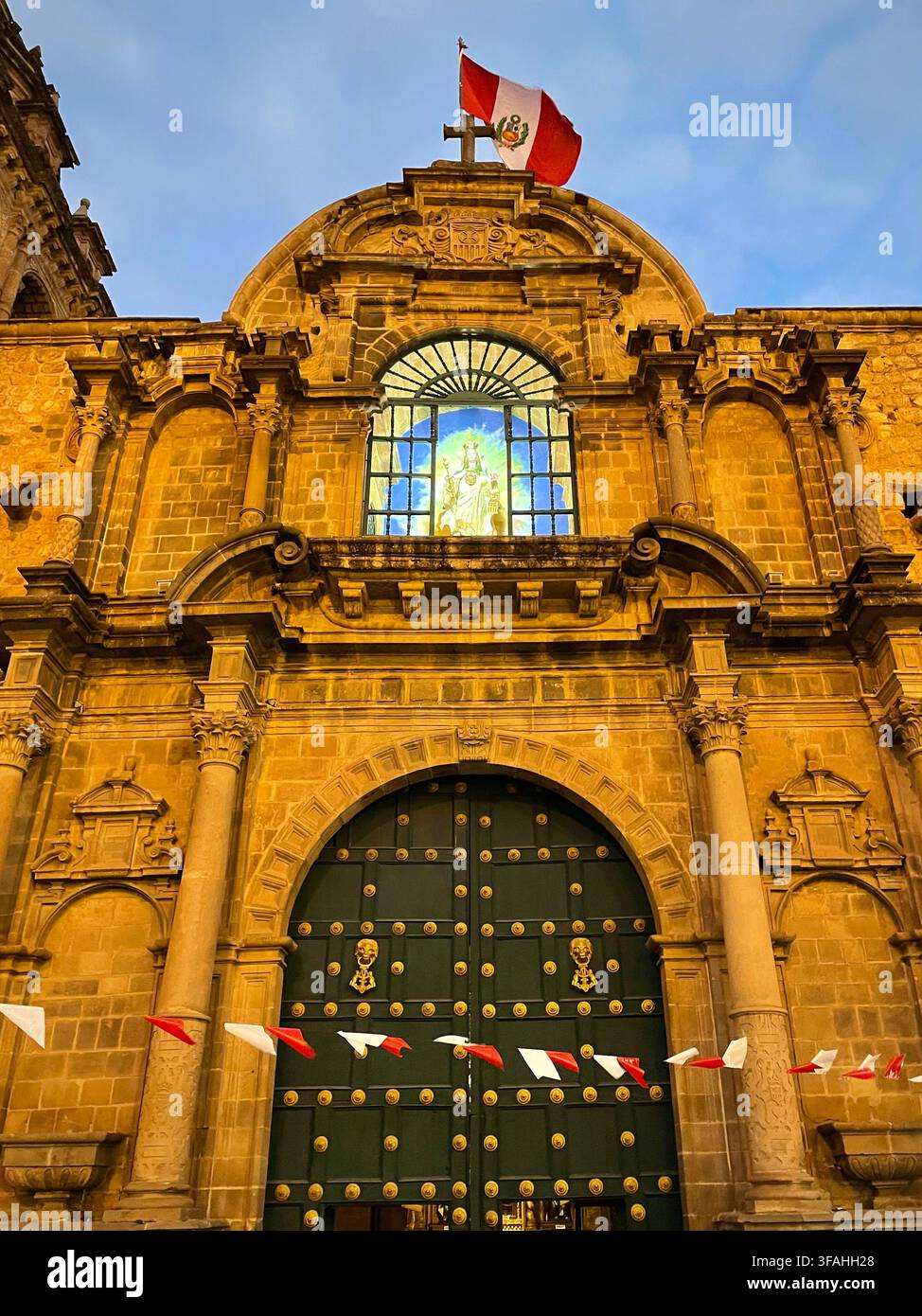 Église historique avec drapeau péruvien au coucher du soleil (Cusco, Pérou) Banque D'Images
