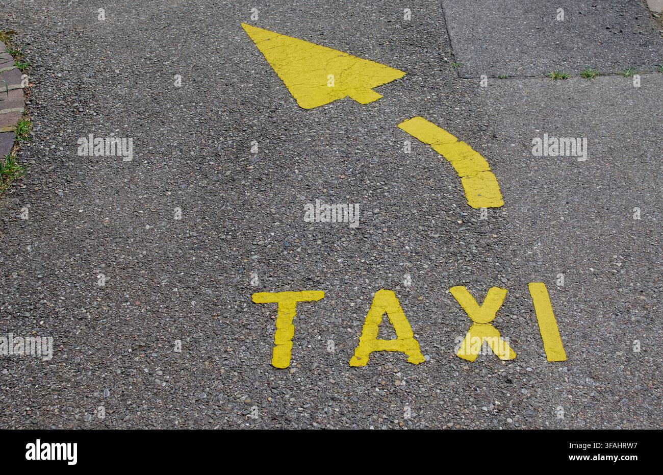 Vue en hauteur du mot TAXI et d'une flèche directionnelle incurvée peinte en jaune sur l'asphalte à Lugano, Suisse. Concept pour les transports urbains Banque D'Images