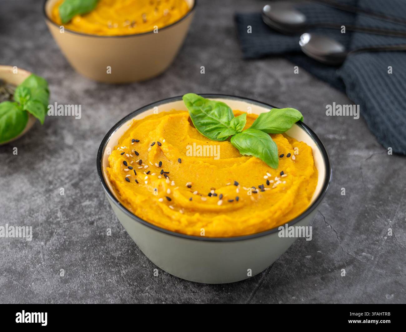Soupe de citrouille maison garnie de graines de citrouille et d'herbes, servie avec des tranches de pain rustique Banque D'Images
