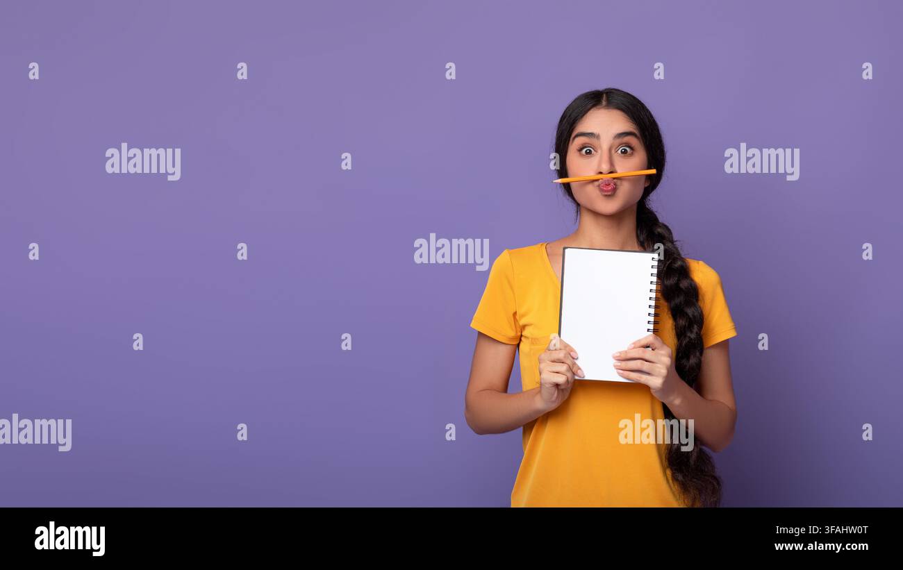 Drôle de dame indienne tenant le stylo comme la moustache sur fond violet Banque D'Images
