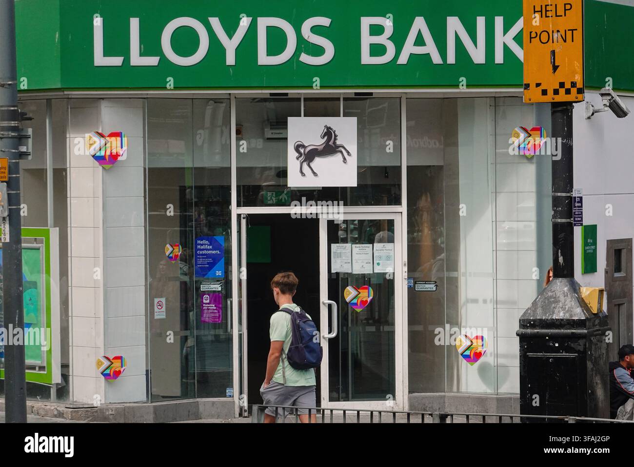 Un jeune homme avec un sac à dos passant devant l'entrée d'une succursale de la Lloyds Bank à Liverpool, Royaume-Uni. Banque D'Images