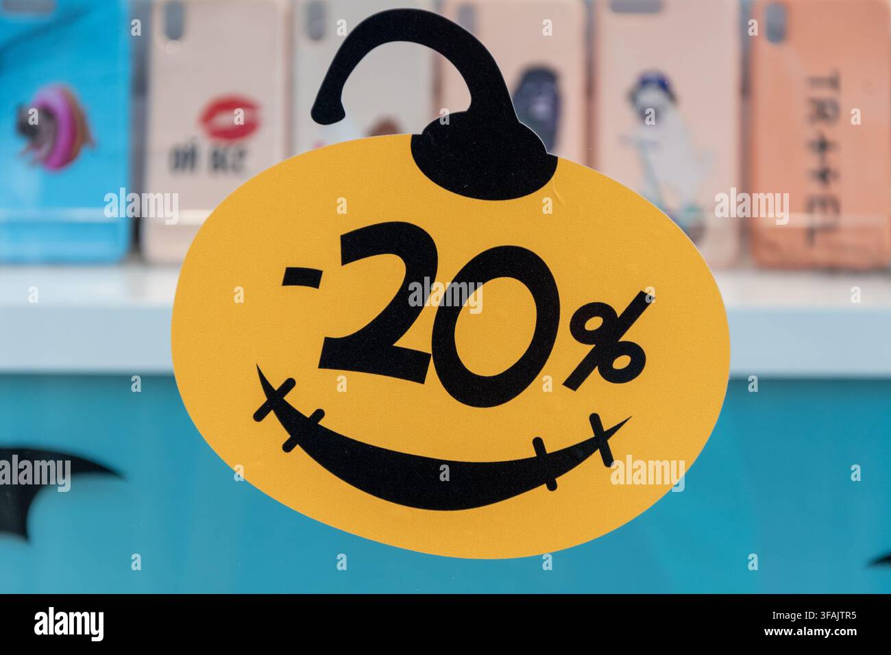 Un étiquette jaune de réduction de vingt pour cent est suspendue devant un affichage de vente au détail flou. Banque D'Images