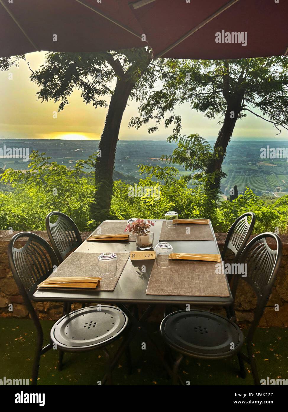Table extérieure réservée pour un dîner romantique au coucher du soleil sur les collines. Un concept de tranquillité, de vie lente et d'évasion exclusive dans la nature italienne. Banque D'Images