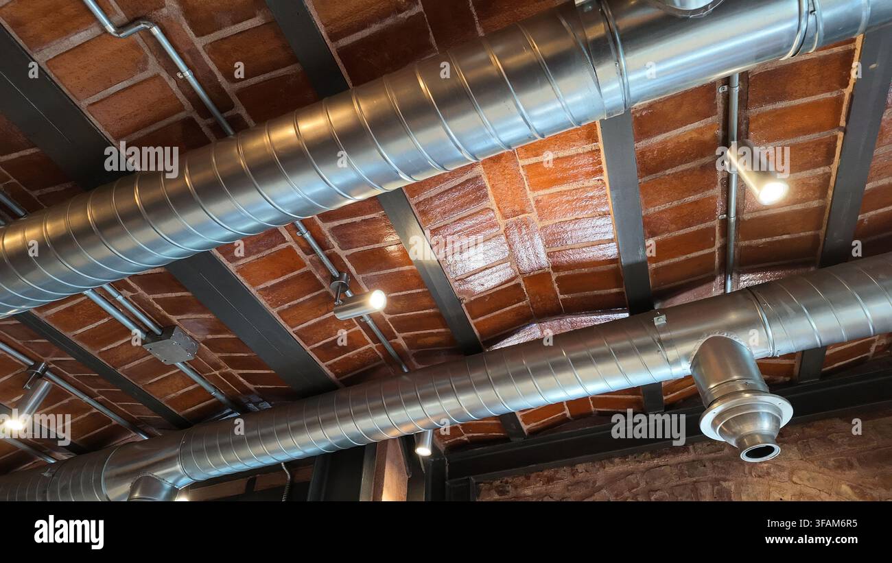 un système de ventilation industrielle et de climatisation installé le long d'un plafond apparent Banque D'Images