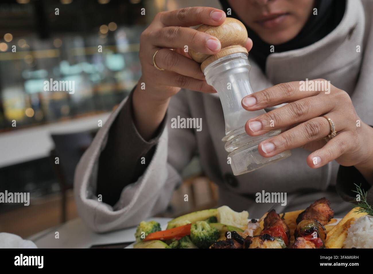 Femme assaisonne des aliments avec du sel à une table de restaurant Banque D'Images