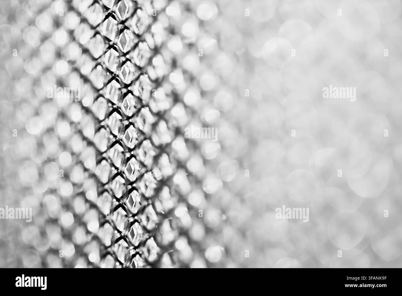 Maille argentée se fondant dans un flou artistique blanc doux avec une mise au point peu profonde et un espace de copie lumineux et aéré pour un fond texturé abstrait Banque D'Images