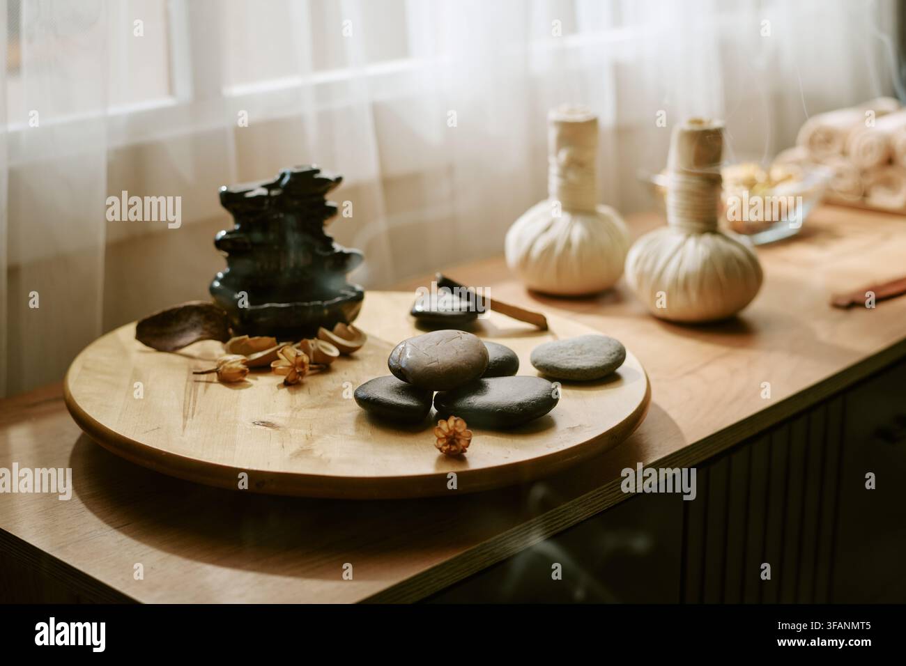 Accessoires de spa et pierres de massage disposés sur une table en bois Banque D'Images