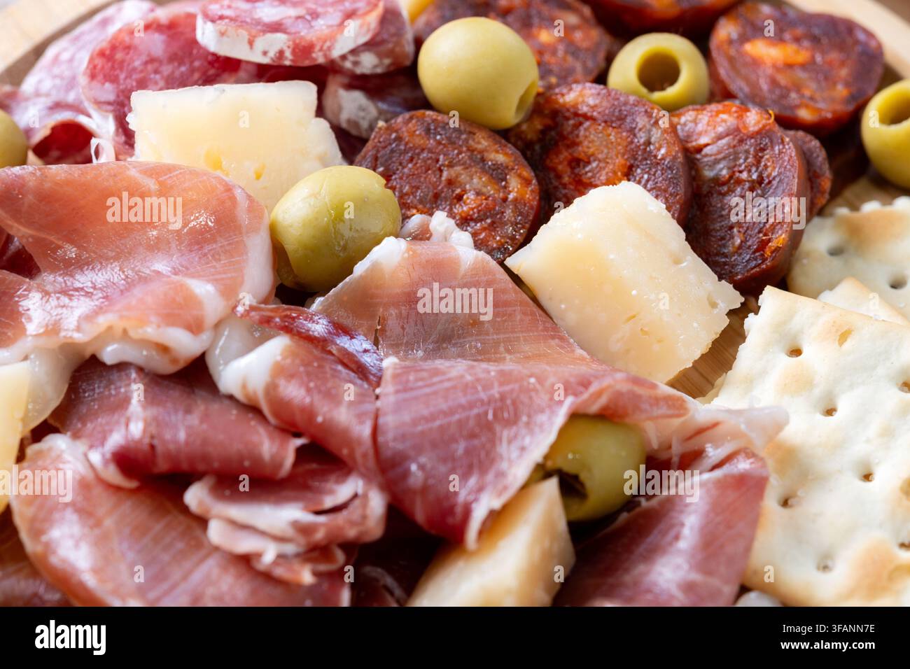 Plateau de charcuterie espagnole avec des viandes séchées, du fromage et des olives sur une assiette en bois Banque D'Images